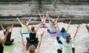 Frauen beim Yoga auf einem Felsvorsprungs sitzend
